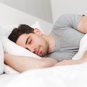 Man sleeping peacefully in bed, showing the benefits of quality sleep for recovery, health, and fitness.