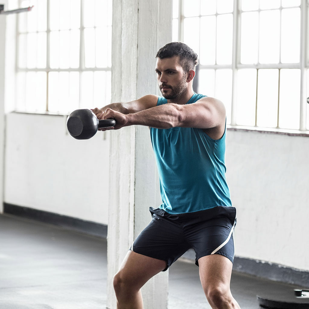 Man performing a kettlebell swing in the gym, representing motivation, discipline, and consistency in training and working out.